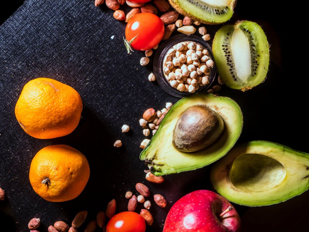 Miks „teadmisest“ ei piisa – ja mida ma õppisin erivajadustega inimeste toetamisest ja toidust A vibrant arrangement of fruits and nuts on a black background featuring kiwi, avocado, oranges, apple, and peanuts.