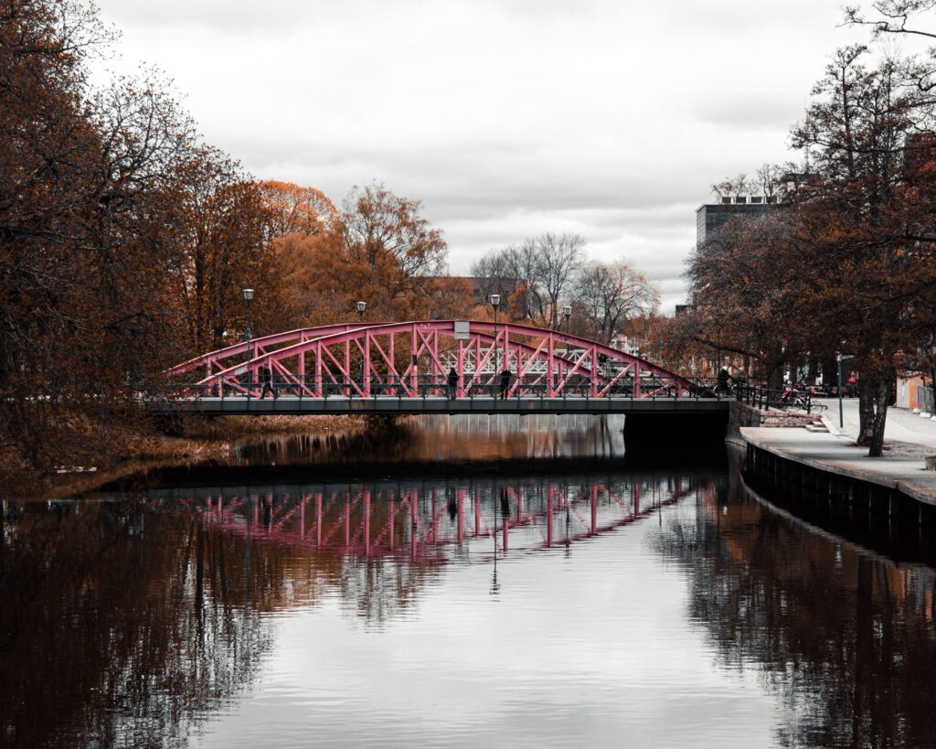 Kui kogemust peab tõestama A striking pink bridge reflects on a calm river amidst Uppsala's autumn scenery, Sweden.