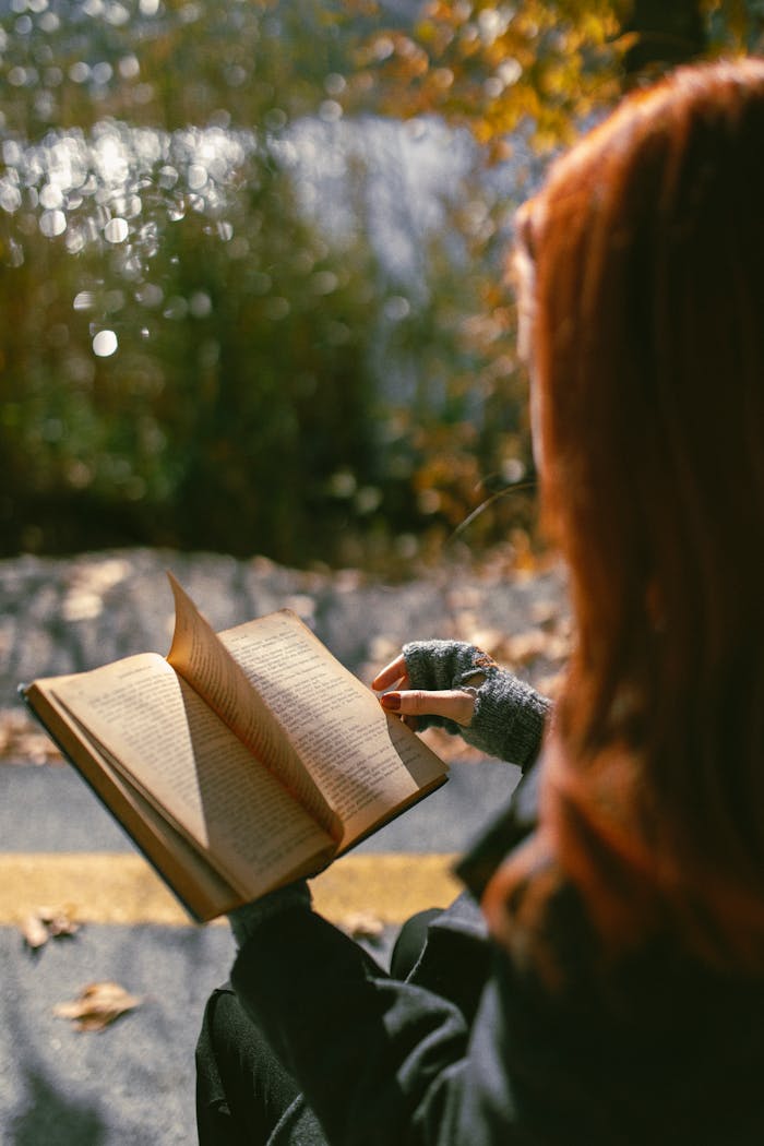Kuidas mõnikord saavad küsimustest vastused A woman reads a book outdoors in an autumn park with sunlight filtering through the trees.