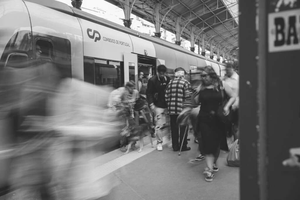 Millal on õige aeg? A black and white scene of commuters at a Lisbon train station, showcasing urban movement.