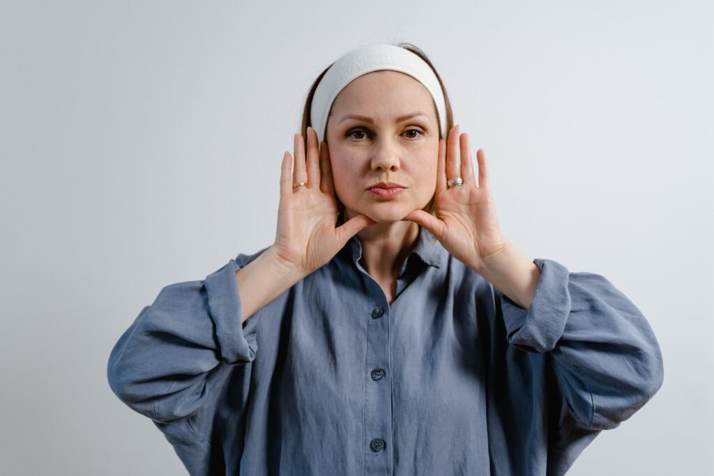 Kui vaikus õpetab kuulama – mõtteid erivajadusest, empaatiast ja kliendikesksusest Portrait of a woman in a blue shirt with hands on her face, wearing a headband, on a white background.