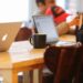 Group working in a cozy cafe with laptops and coffee mugs on a shared table.