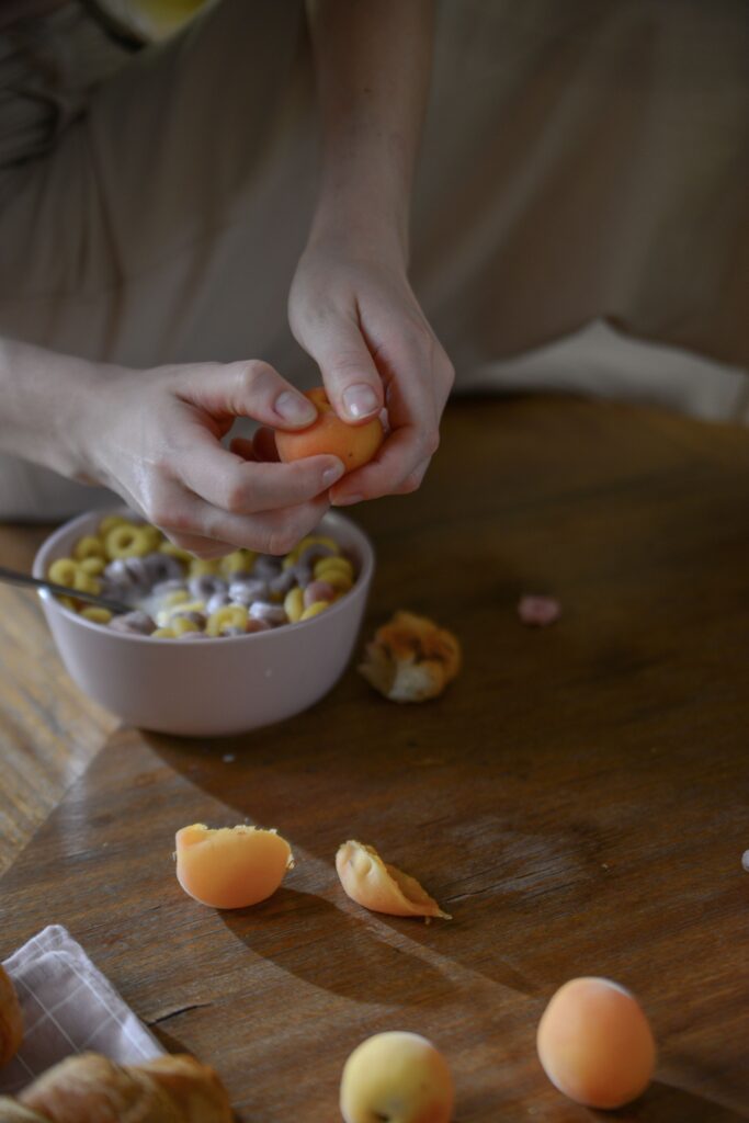 Kui vaikus õpetab kuulama – mõtteid erivajadusest, empaatiast ja kliendikesksusest Hands peeling apricots over a bowl of cereal on a wooden table. Fresh and natural breakfast scene.