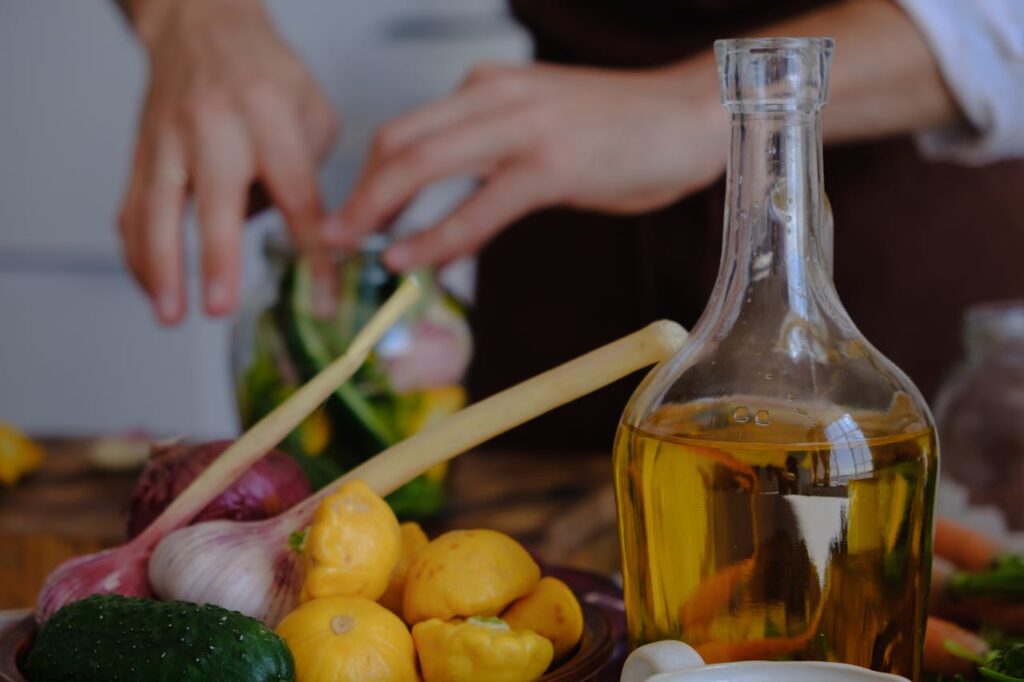 Tervisliku eluviisi toetamine erivajadustega inimestele Hands preparing vegetables with olive oil, garlic, and squash in a kitchen setting.