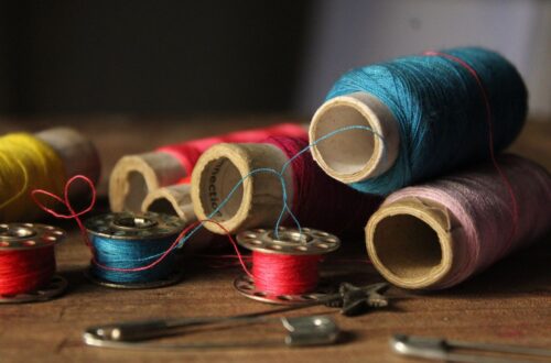 Vibrant spools of thread and sewing tools on a wooden table, perfect for crafting themes.