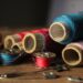 Vibrant spools of thread and sewing tools on a wooden table, perfect for crafting themes.