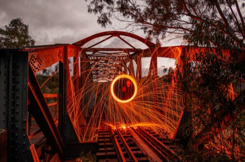 Captivating long exposure shot of light painting with sparks on an old railway bridge at night.