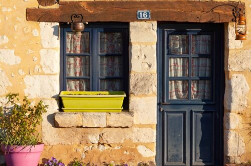 Rustic cottage entrance with blue door and windows in Mortagne-au-Perche, France.