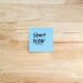 Blue Post-It note with 'Start Now' on light wooden background, inspiring action.