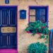 Charming vibrant house facade with colorful door, window flowers, and mailbox.