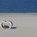 A serene scene of an elderly couple sitting on a bench by the sea, embraced by a heart-shaped structure.