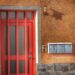 Vibrant red door with mailboxes on textured orange wall, modern design.