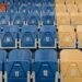 Uniform rows of red, blue, and yellow stadium seats with numbers visible.